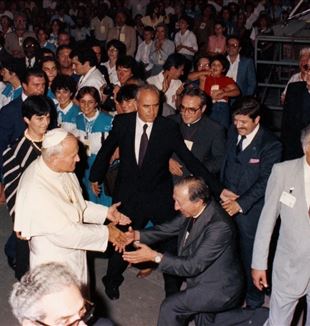 Don Giussani knielt bij de aankomst van Johannes Paulus II op de Meeting in de zomer van 1982. Links van de paus staat Emilia Guarnieri (© Meeting Rimini)